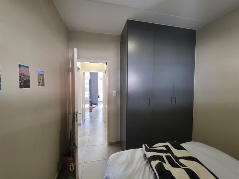 A bedroom featuring a dark built-in wardrobe and tiled flooring, with a view leading into the hallway.
