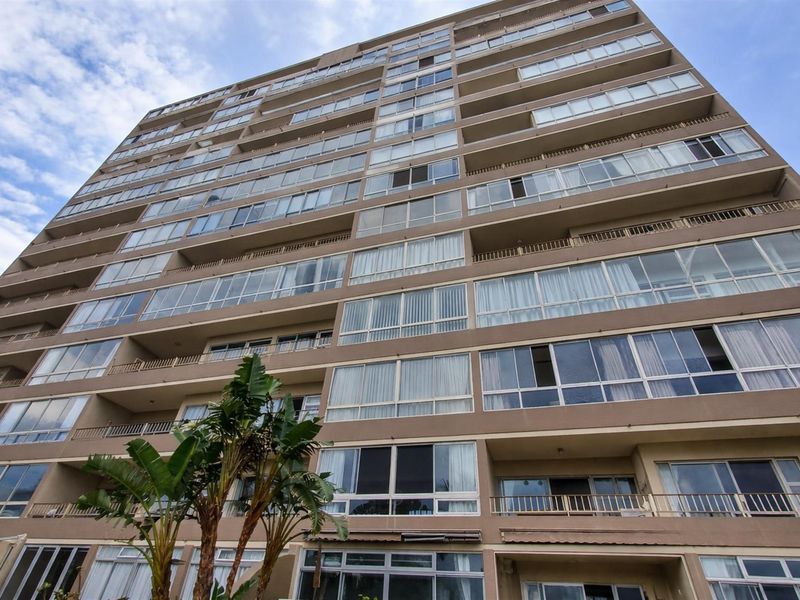 A low-angle view of a multi-story apartment building facade featuring numerous balconies and large glass windows.