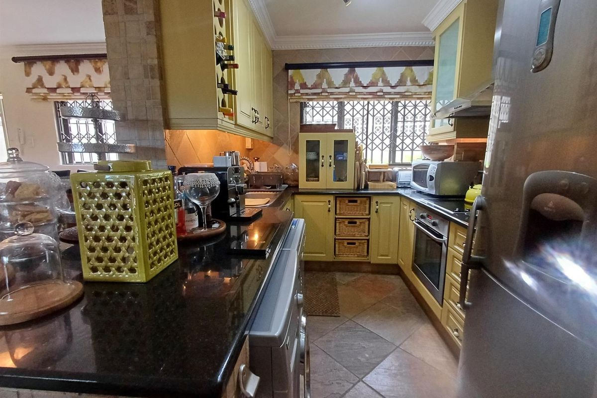 A functional kitchen featuring granite countertops, built-in cabinetry, an integrated oven, and tiled flooring, offering a classic layout with ample storage space.