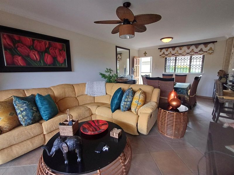 Open-plan living and dining area featuring tiled flooring, a ceiling fan, and security bars on the windows.