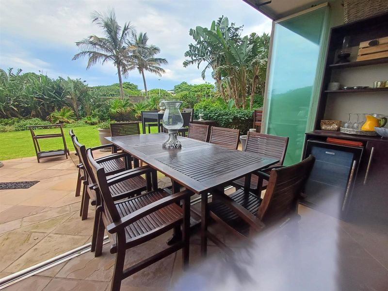A spacious covered patio featuring paved flooring and seamless access to the garden, ideal for outdoor dining and entertaining.