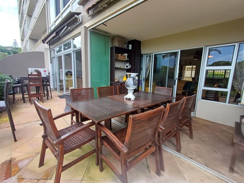 Spacious covered patio featuring tiled flooring and large sliding glass doors, providing a seamless transition between indoor and outdoor living areas.