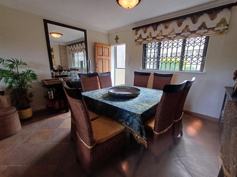 A dining room featuring tiled flooring, decorative ceiling cornicing, and a window fitted with security bars.