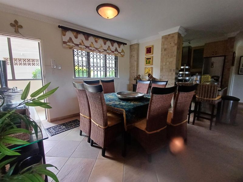 Open plan dining area featuring tiled flooring, a decorative stone-clad pillar, and direct access to an outdoor patio space.