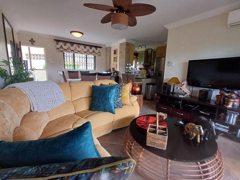 Open-plan living and dining area featuring tiled floors, a ceiling fan, and an integrated kitchen space with cabinetry.