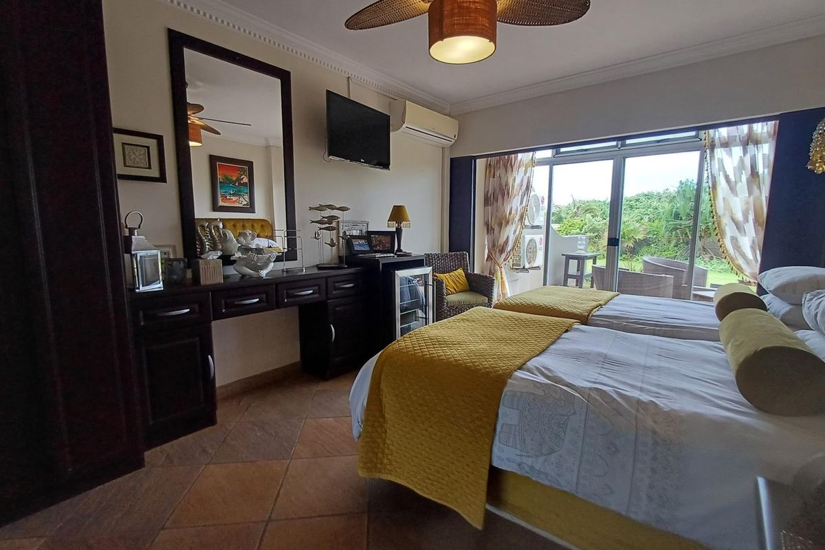 A well-maintained bedroom featuring tiled flooring, crown molding, a ceiling fan, and a split-system air conditioner, with direct access to an outdoor patio area.