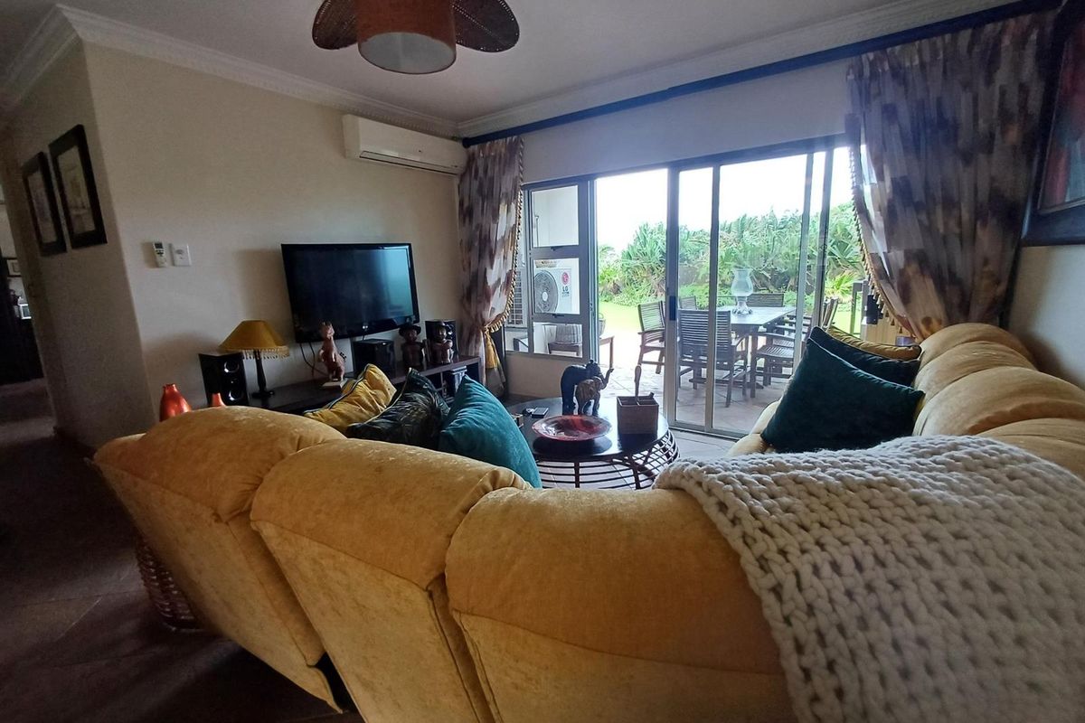 A comfortable living room featuring tiled flooring, crown molding, a ceiling fan, and split-system air conditioning, with direct access to an outdoor patio area.