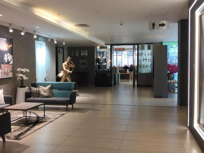 A modern, well-maintained apartment building lobby featuring tiled flooring, recessed ceiling lighting, and directional signage leading to communal facilities.