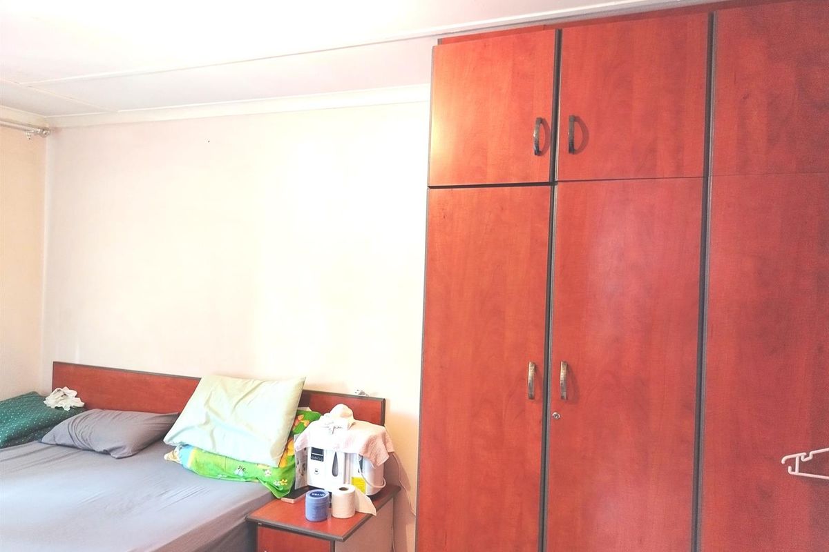 A bedroom featuring a large built-in wooden wardrobe with ample storage space.