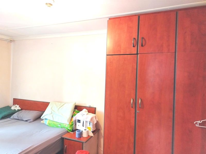 A bedroom featuring a large built-in wooden wardrobe with ample storage space.
