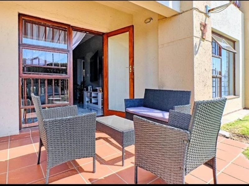 A covered patio area featuring tiled flooring and direct access to the interior through a wooden door frame.