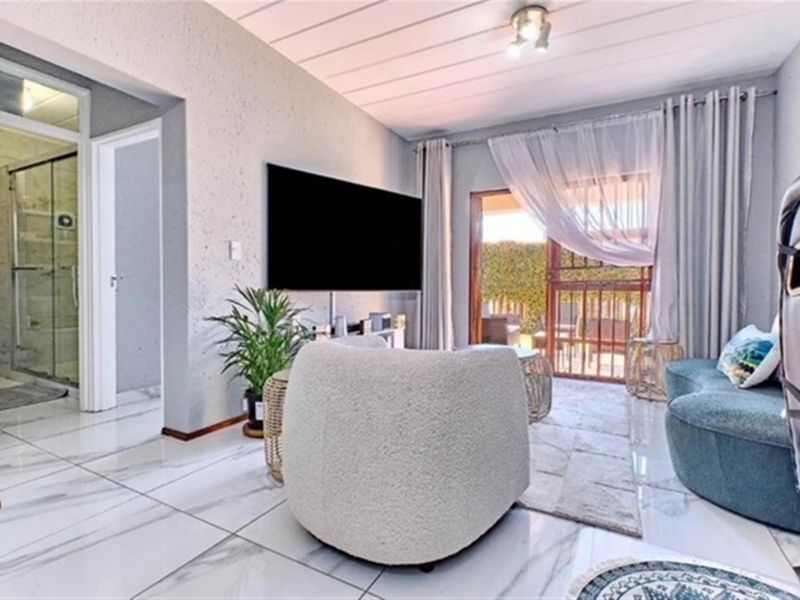 Modern living room featuring polished marble-look floor tiles, textured walls, and direct access to an outdoor patio through a sliding glass door.