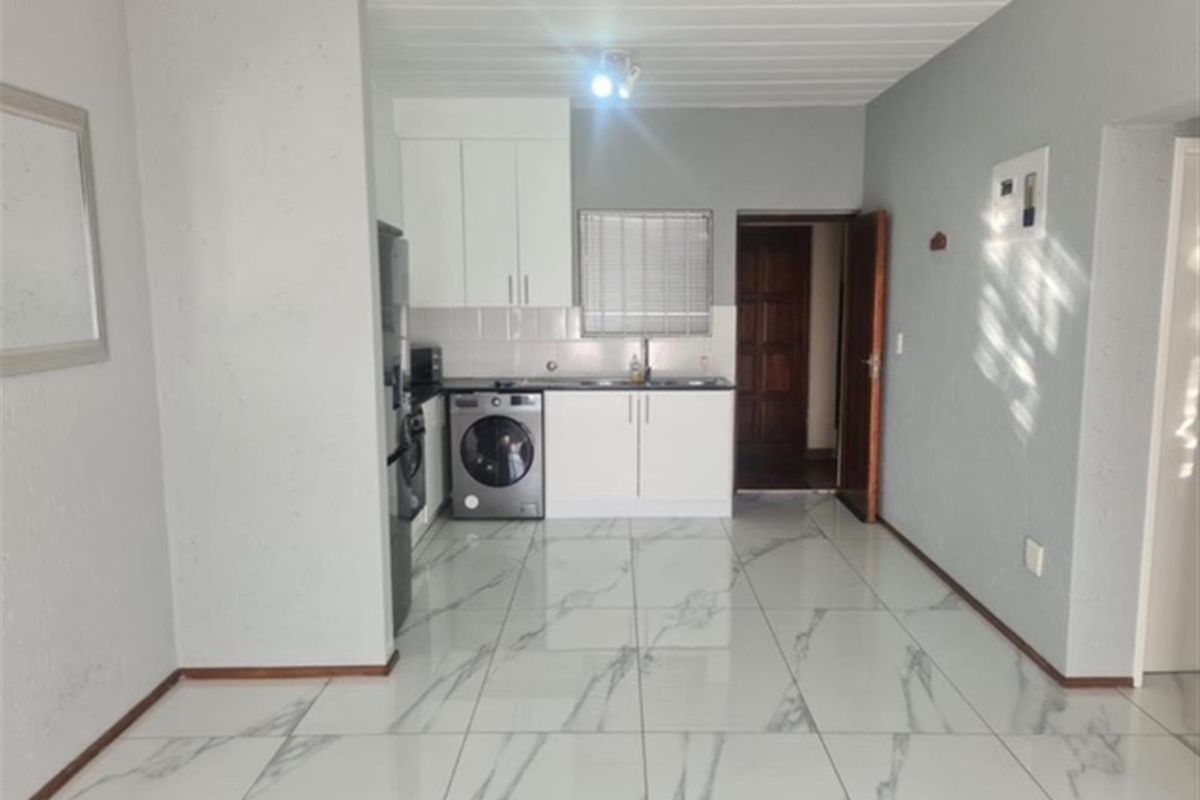 A clean, modern kitchen featuring white cabinetry, marble-look floor tiles, and a tiled backsplash, offering a bright and functional workspace.