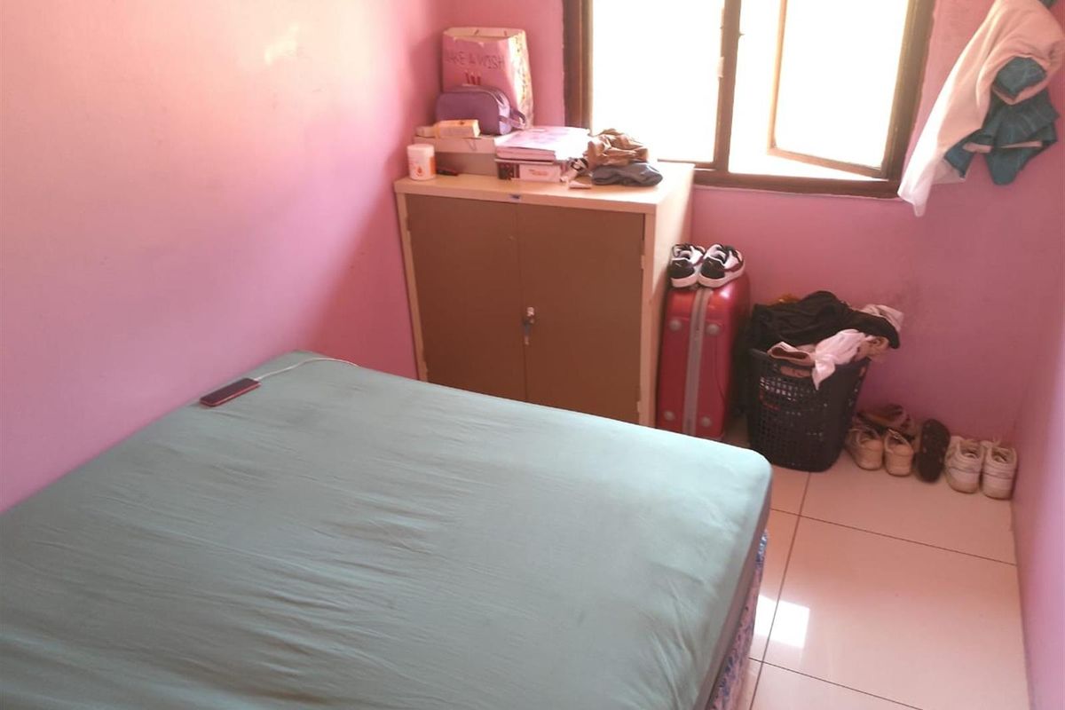A compact bedroom featuring tiled flooring and a window, currently requiring cosmetic updates to the wall finishes.