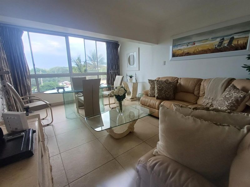 A bright open-plan living and dining area featuring large floor-to-ceiling windows that provide natural light and scenic views.