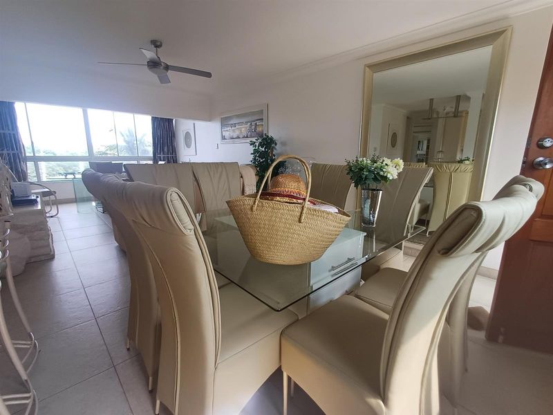 Open plan living and dining area featuring tiled flooring, a ceiling fan, and a large wall-mounted mirror.