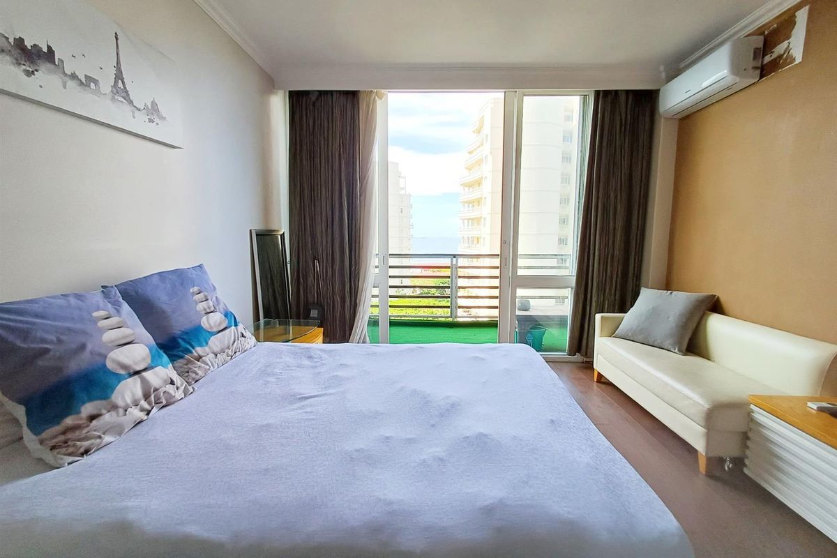 A bedroom featuring laminate flooring, a split-system air conditioner, and direct access to a private balcony with exterior views.