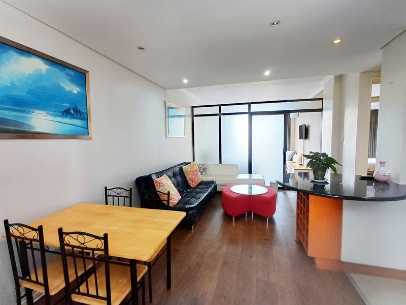 Open-plan living and dining area featuring laminate flooring, recessed lighting, and a breakfast bar with integrated wine storage.