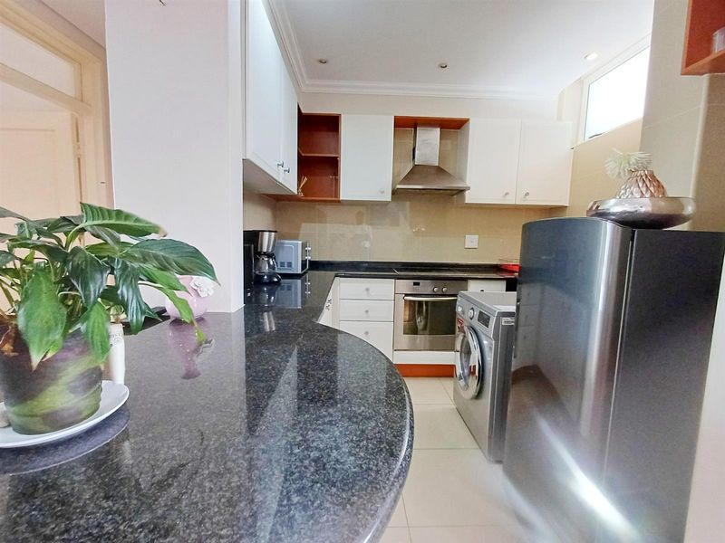 A functional kitchen featuring granite countertops, a breakfast bar, built-in oven, extractor fan, and ample cabinetry for storage.