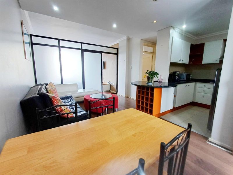 Open-plan living and kitchen area featuring a breakfast bar, built-in cabinetry, and a modern glass partition wall separating the living space.