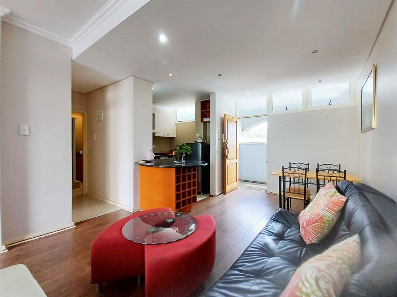 Open plan living and kitchen area featuring laminate flooring, recessed lighting, and a compact kitchen with granite countertops and integrated wine storage.