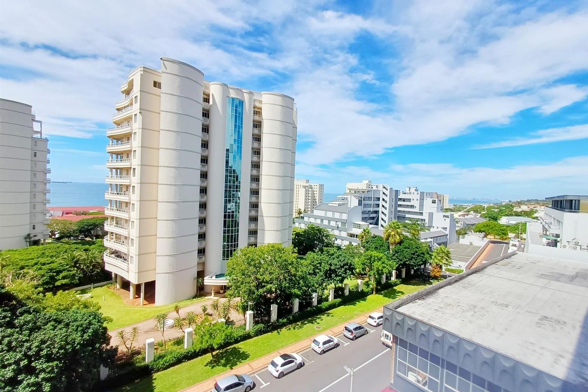 Elevated view of the apartment complex and surrounding neighborhood, showcasing the building architecture, landscaped grounds, and street access.