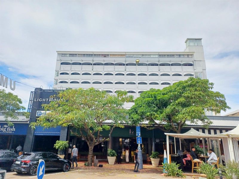 Exterior view of a multi-story apartment building featuring a commercial ground floor with retail and dining spaces.