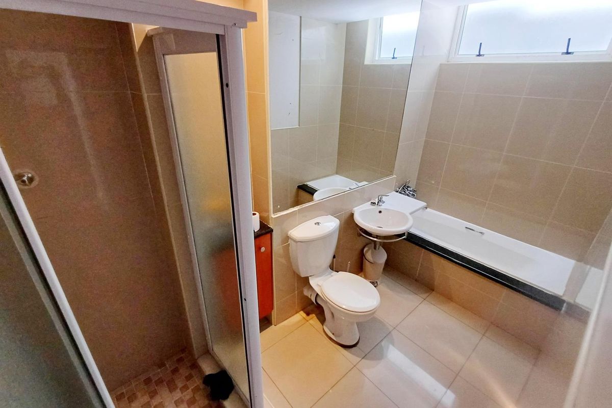 A functional bathroom featuring a separate shower enclosure, a bathtub, a pedestal basin, and a toilet with neutral wall and floor tiling.