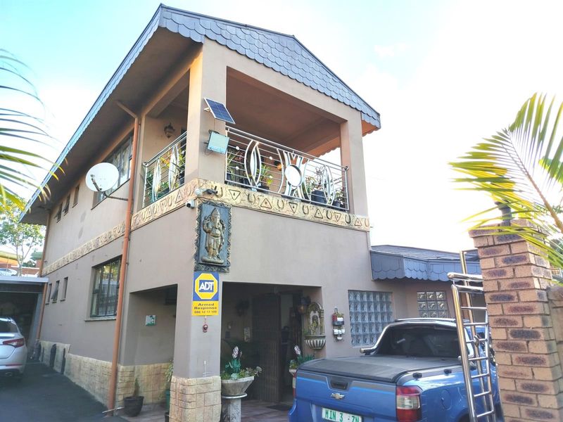 Front elevation of a two-story house featuring a covered balcony with stainless steel balustrades, decorative facade detailing, and integrated solar lighting.