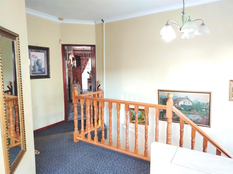 A carpeted upper-level hallway featuring a traditional timber balustrade and coved ceilings, providing access to adjacent rooms.