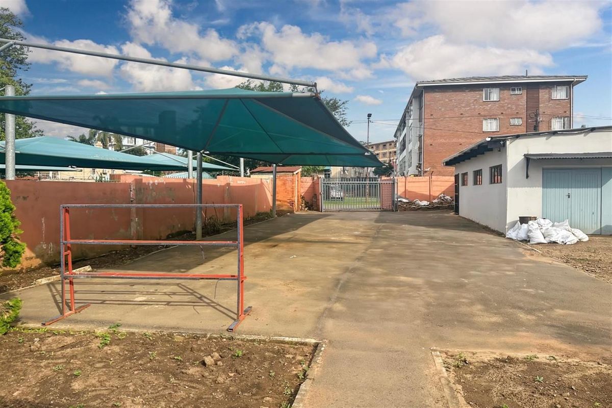 Outdoor paved parking area featuring shade cloth structures, perimeter walling, and gated access, suitable for business or residential vehicle storage.