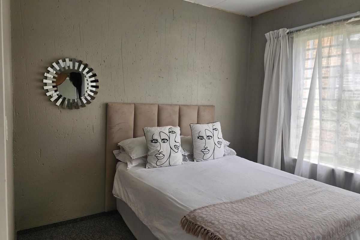 A bedroom featuring textured walls and a window fitted with security bars, offering a functional space ready for cosmetic updates.