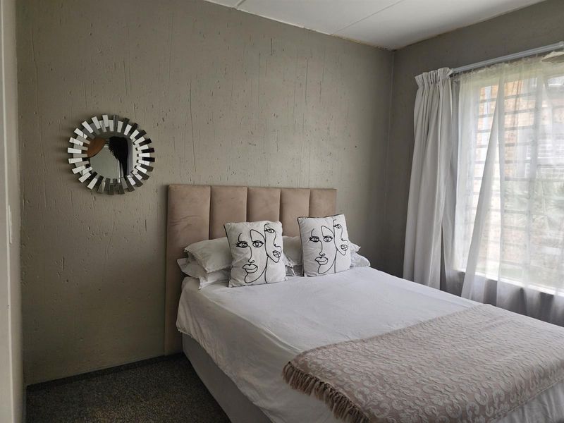 A bedroom featuring textured walls and a window fitted with security bars, offering a functional space ready for cosmetic updates.