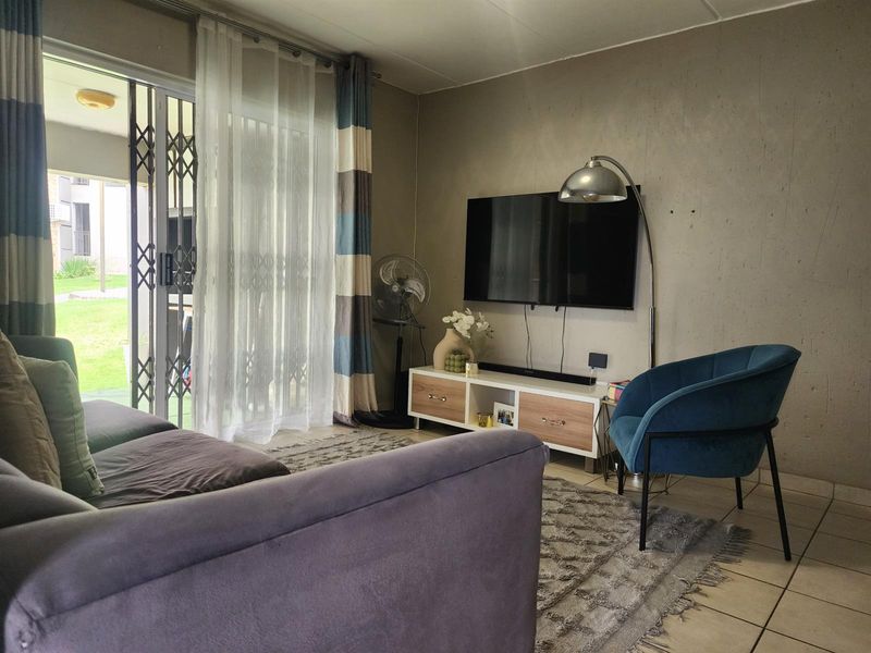 A living room featuring tiled flooring and a sliding glass door with a security gate, providing access to the outdoor area.