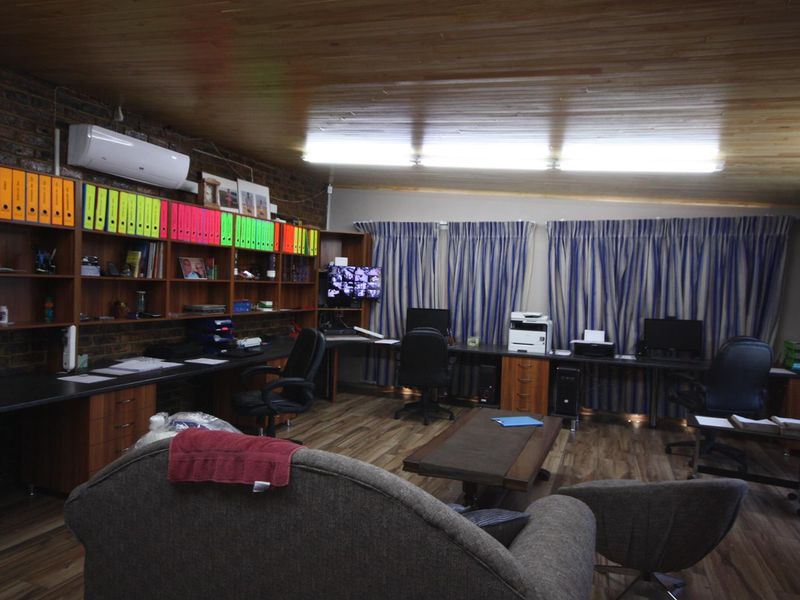 Spacious home office featuring built-in timber cabinetry, exposed brick wall, laminate flooring, and a timber-clad ceiling with integrated air conditioning.
