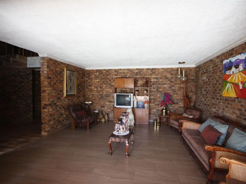 Spacious living room featuring rustic exposed brick walls and modern tiled flooring, offering a warm and character-filled atmosphere.