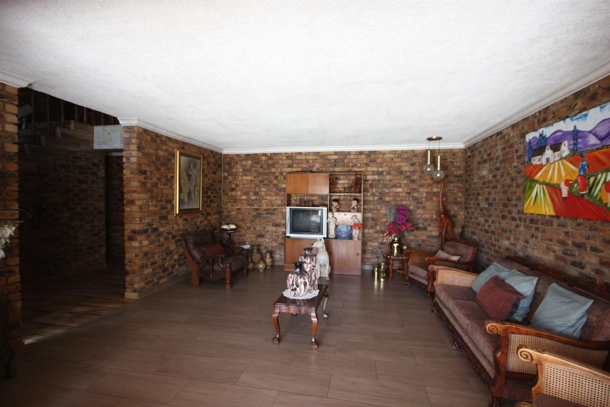 Spacious living room featuring rustic exposed brick walls and modern tiled flooring, offering a warm and character-filled atmosphere.