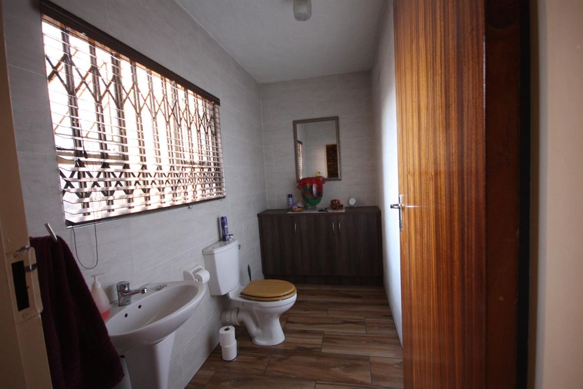 A functional bathroom featuring tiled walls and flooring, a pedestal basin, a toilet, and a built-in vanity cabinet for storage.
