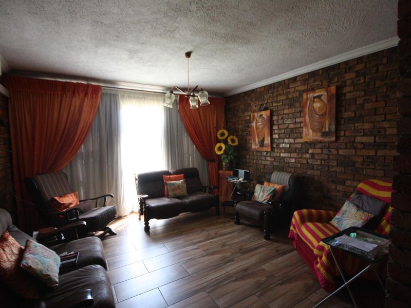 A living room featuring exposed brick walls, wood-look tile flooring, and a coved ceiling with a central light fixture.