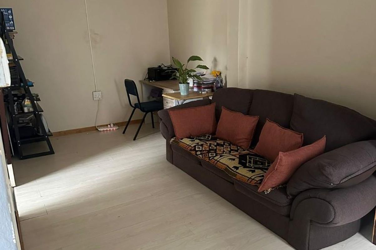 A living room area featuring light-toned laminate flooring and neutral wall finishes, providing a functional space for relaxation.