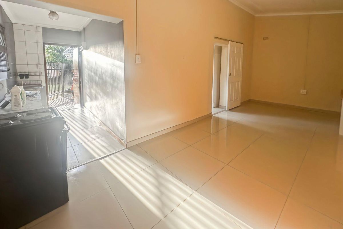 An open-plan living and kitchen area featuring tiled flooring, neutral walls, and direct access to an outdoor space.