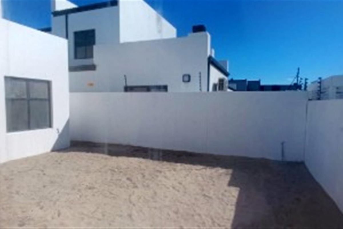 A rear exterior view of the property featuring a private, enclosed courtyard area with boundary walls and direct access to the main dwelling.