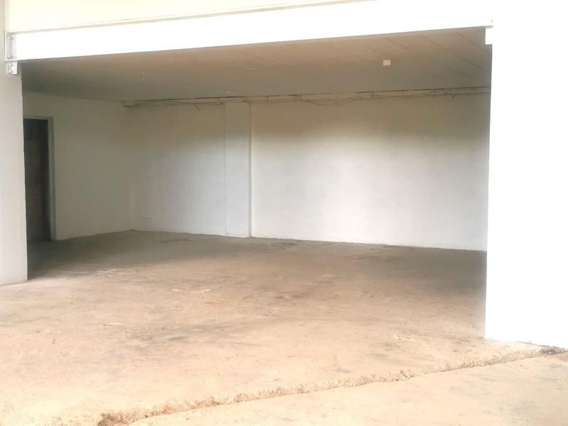 An open-plan commercial space featuring a concrete floor, exposed structural beam, and basic utility access, suitable for a variety of business configurations.