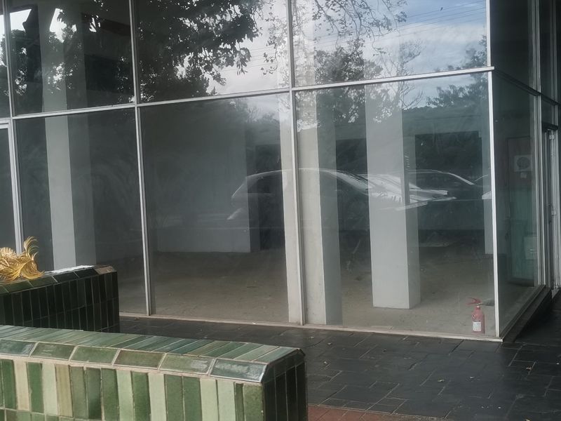 Commercial property exterior featuring a large glass facade, stone paved entrance area, and a tiled retaining wall.