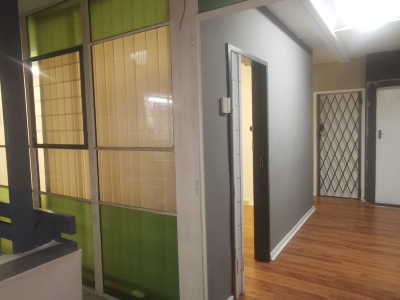 A commercial hallway featuring laminate flooring, a glass partition wall, and secure access doors.