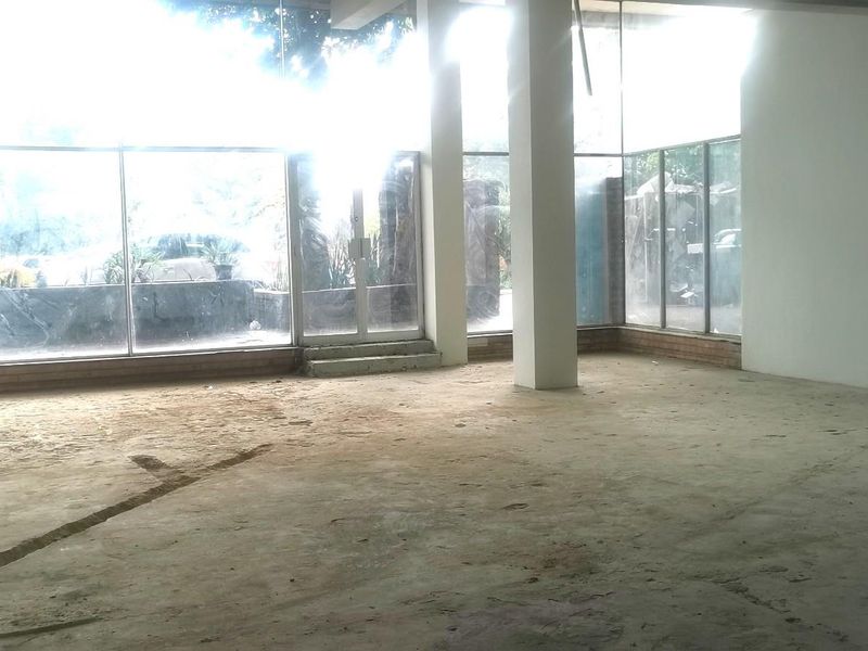 An expansive, open-plan commercial space featuring floor-to-ceiling glass windows, structural columns, and unfinished concrete flooring, offering a blank canvas for custom fit-out.
