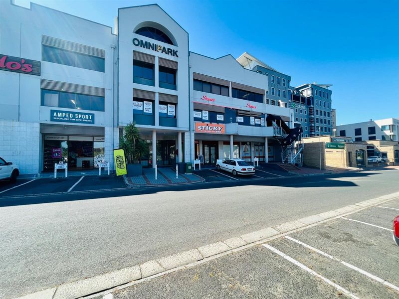 Front elevation of the Omnipark commercial building featuring multiple storefronts, paved parking, and modern architectural facade elements.