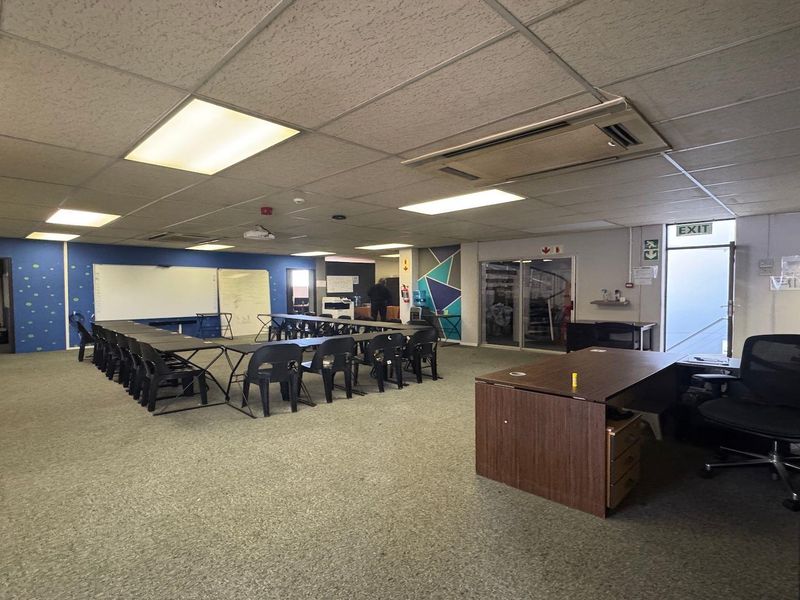 A functional commercial office space featuring a suspended ceiling, recessed lighting, ducted air conditioning, and carpeted flooring, suitable for a training or meeting room.