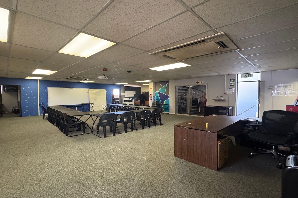 A functional commercial office space featuring a suspended ceiling, recessed lighting, ducted air conditioning, and carpeted flooring, suitable for a training or meeting room.