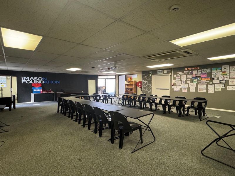 A spacious commercial office or training room featuring a suspended ceiling, recessed lighting, ducted air conditioning, and carpeted flooring.